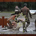 Άνδρες παίζουν ράγκμπι σε λασπωμένο γήπεδο με ένα κομμάτι παζλ στο επίκεντρο